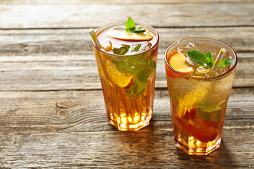 Refreshing iced peach tea in glasses on wooden table, closeup. Space for text