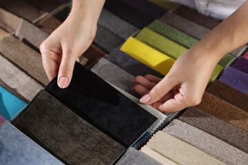Woman choosing fabric among different samples indoors, closeup