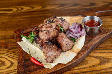 fried kebab with onions and herbs on a wooden board