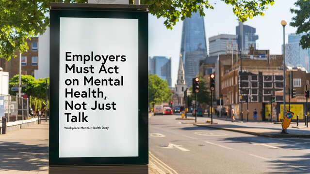 Bus stop billboard poster reading &ldquo;Employers must act on mental health, not just talk&rdquo; on London street with city buildings