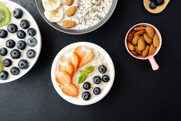 Assorted breakfast oatmeal bowls with fruits chia seeds and almonds on black background