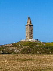 Historic Tower of Hercules lighthouse on coastal hill against clear blue sky