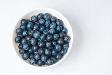Fresh blueberries in a white bowl on a light background ready for snacking