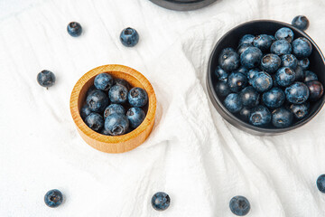 Fresh blueberries arranged in bowls on a light linen surface