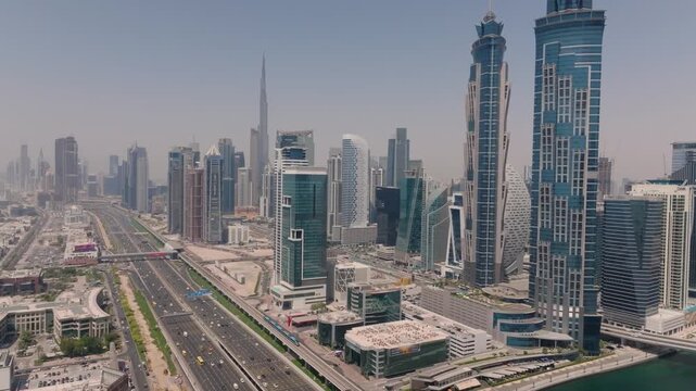 Dubai, UAE - 01 August 2025: Aerial view of a modern cityscape with towering skyscrapers and the iconic Burj Khalifa piercing through a hazy sky.