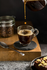 Pouring black coffee in a glass cup, energy coffee drink