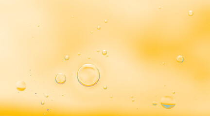 Soft abstract close-up of oil bubbles floating in warm golden-yellow liquid. Transparent oil bubbles in yellow liquid background