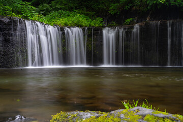 Obraz premium Tall, even-flowing waterfall cascading in a smooth, steady sheet of water.