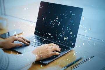 Person working on laptop with digital binary code overlay in modern office environment, symbolizing data, internet, and cloud technology concepts.