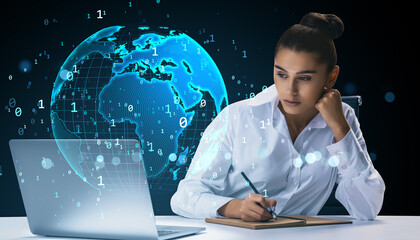 Businesswoman working at desk with laptop and writing notes, digital globe with binary code in background representing global cyberspace data network.