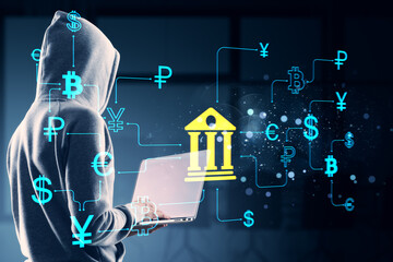 Hacker in hoodie using laptop with digital banking and global currency icons on dark background showing cyber security and fintech threats concept.