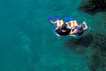 Relaxed family moment floating on a transparent turquoise lagoon in Riviera Maya, with vivid water tones and warm sunlight ideal for lifestyle, travel, and eco-luxury themed commercial use.