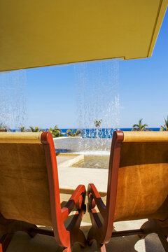 Modern lounge chairs under bright shade facing a tropical beach on the Mexican coast, with vibrant light and a luxurious setting perfect for travel, vacation, and leisure-related advertising.