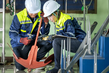 Vernier Caliper: Two Engineers Teamwork Performing Anchor Inspection for Precision Marine Equipment Mentor Teaching Anchor Measurement Process Technicians in Helmets Inspecting Anchor Detail.