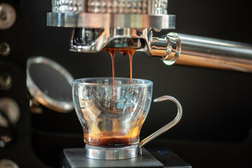 Coffee Machine Detail: Close Up of Portafilter and Glass Cup during Espresso Process Rich Espresso: Dark Coffee Dripping with Crema into Transparent Glass Specialty Dark Coffee Flowing into Glass Cup.