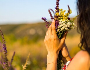 Woman holding a bouquet of wildflowers in a field at sunset