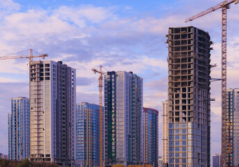 Fototapeta premium Construction of buildings and high-rise cranes against the sky
