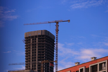 Fototapeta premium Construction of buildings and high-rise cranes against the sky