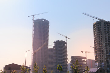 Fototapeta premium Construction of buildings and high-rise cranes against the sky
