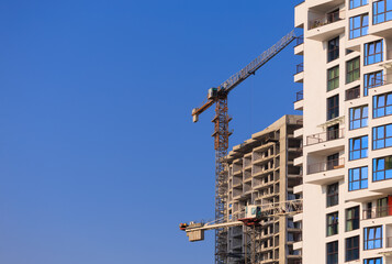 Fototapeta premium Construction of buildings and high-rise cranes against the blue sky