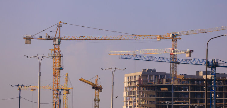 Construction of buildings and high-rise cranes against the sky - Powered by Adobe