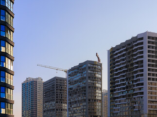 Fototapeta premium Construction of buildings and high-rise cranes against the sky