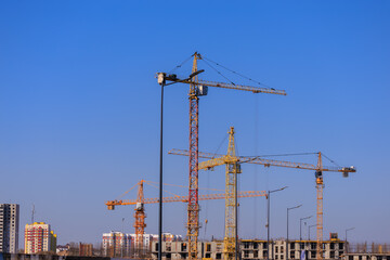 Construction of buildings and high-rise cranes against the blue sky