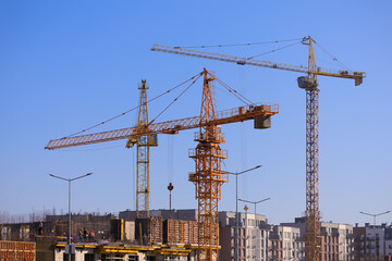 Construction of buildings and high-rise cranes against the sky