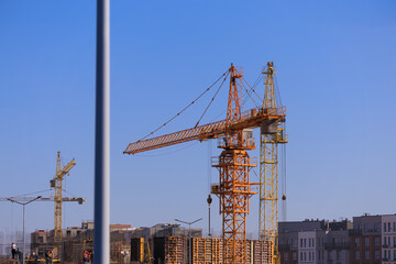 Construction of buildings and high-rise cranes against the blue sky