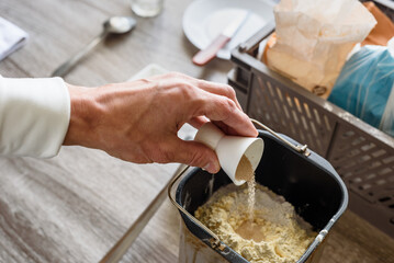 Man preparing ingredients for baking bread and adding yeast, closeup photo. Preparing dough for...