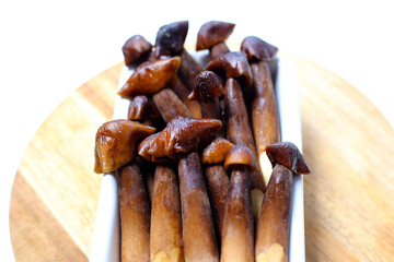 Termite mushrooms with long stems, white tips, and dark brown caps.