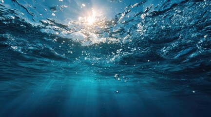Sunlight streams through deep, vibrant blue water.  Sunbeams pierce the surface, illuminating bubbles and ripples