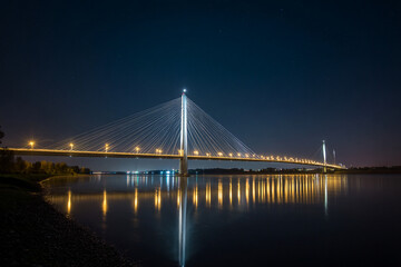 Obraz premium Modern suspension bridge at night, illuminated cables reflecting in still water below