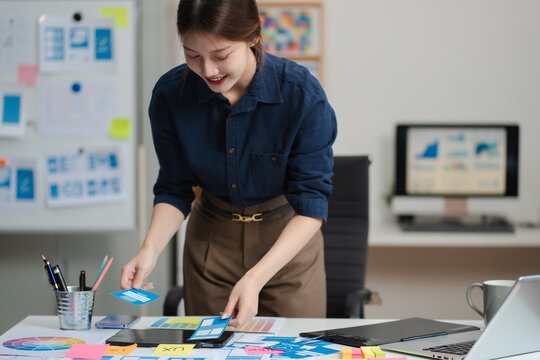 Female coder or developer working using a computer display and smartphone in problem solving at workplace.