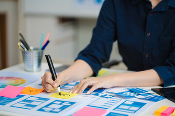 Female coder or developer working using a computer display and smartphone in problem solving at workplace.