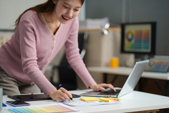 Female coder or developer working using a computer display and smartphone in problem solving at workplace.