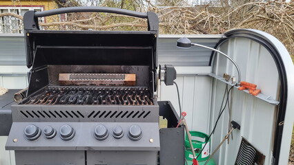 Outdoor barbecue cooker with an open lid standing on a terrace. A modern gas grill, perfect for outdoor cooking and barbecuing. Barbecue gas grill in stainless steel.