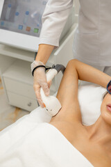 laser hair removal, hair removal procedure, young beautiful smiling brunette lying on a couch in a beauty salon, armpit hair removal, spa and cosmetology concept