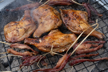 Pieces of chicken grilling outside in a popular street food market in Chinatown, Bangkok, Thailand.