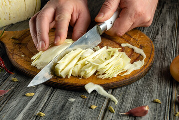 Hands expertly chop fresh cabbage on a wooden board, highlighting the preparation of healthy ingredients. The kitchen's rustic charm adds warmth to the process of meal preparation