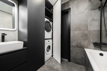 Modern laundry area integrated into stylish bathroom with sleek design and efficient appliances in...