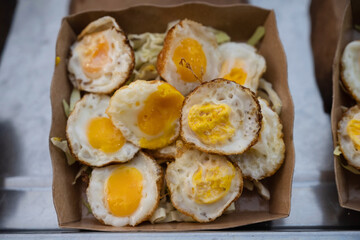 Tasty looking fried quail eggs, known as khai nok kratha in Thai, a popular street food delicacy on display in a traditional night market in Bangkok, Thailand.