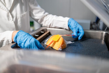 Industrial food packaging. Worker in sterile clothing labeling food product.