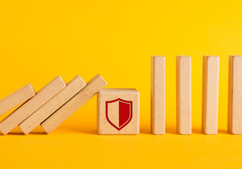 Wooden blocks falling like dominoes stopped by a shield protecting other blocks
