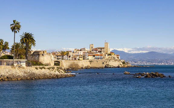 View of the old town with its historic buildings, walls, and the Ch&Atilde;&cent;teau Grimaldi perched on the coast against the azure sea, Antibes, Alpes-Maritimes, France.