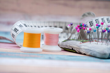 Colorful sewing threads, measuring tape, and pins arranged on a sewing workspace during a creative project