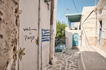 Benvenuti a Paros: vicolo tipico con murales e bandiera greca nell&rsquo;isola delle Cicladi.