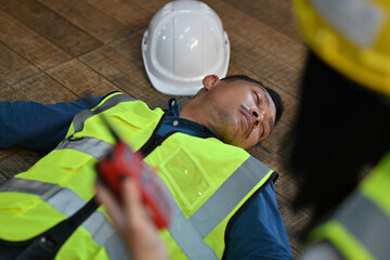 A warehouse worker lying unconscious after an accident, with a hard hat nearby. Focus on workplace safety, emergency preparedness, and immediate medical assistance