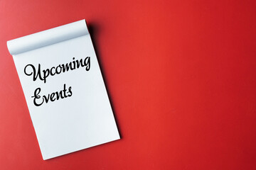 Notebook Displaying 'Upcoming Events' Text on a Bold Red Surface