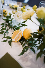 Festive table decor in yellow and white tones with flowers and lemons.